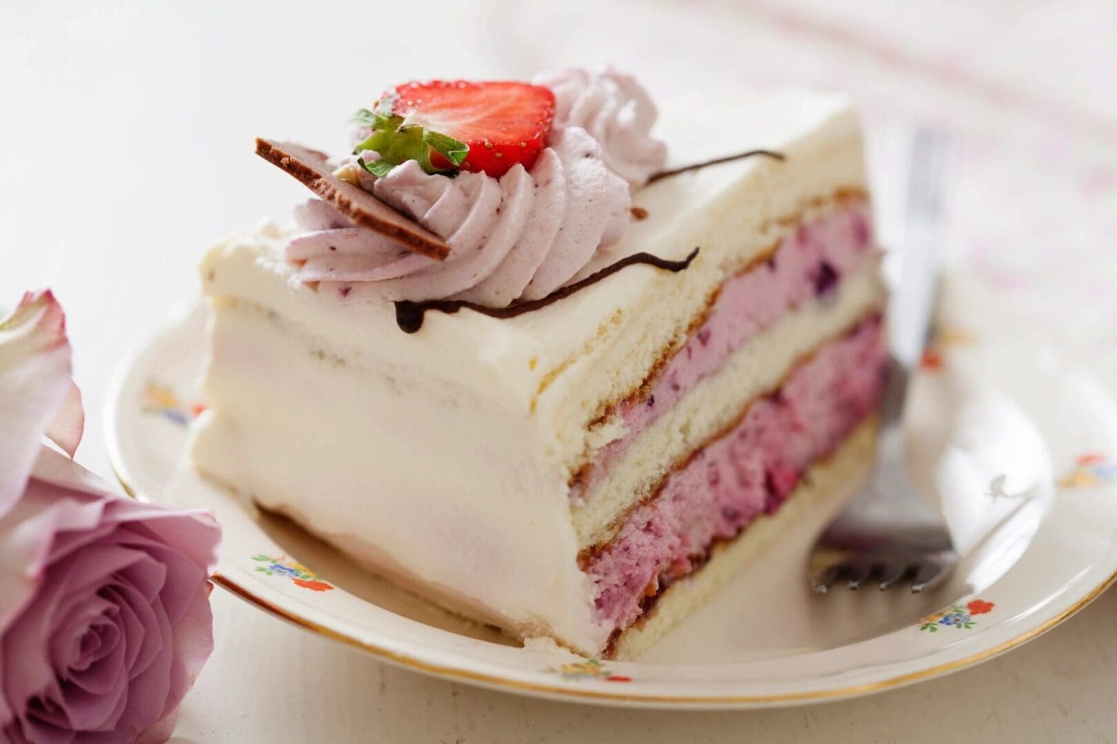 A piece of cake with white frosting and strawberry on top.